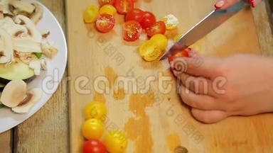 一个女人正在用一把刀切一个黄色和红色的樱桃番茄